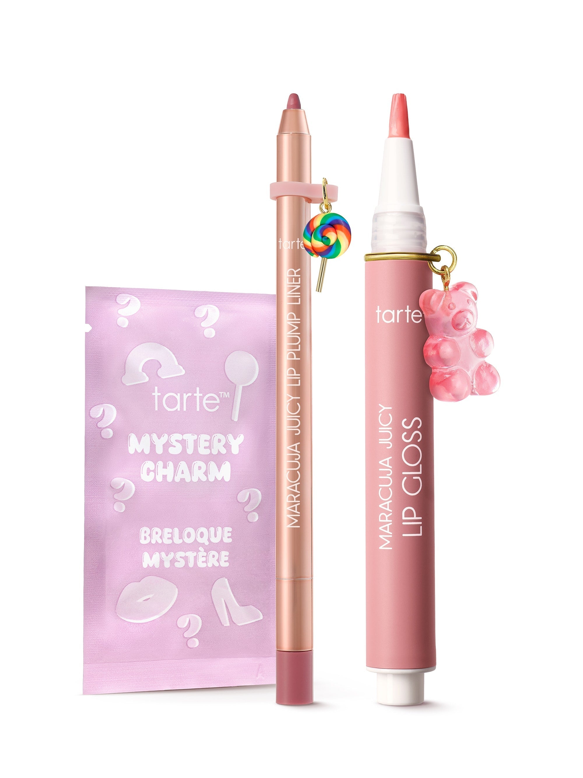 A pink maracuja juicy lip gloss pen and matching lip liner stand upright, each adorned with a small charm, beside a pastel purple mystery charm sachet on a white background.

Text: tarte™ MYSTERY CHARM BRELOQUE MYSTÈRE; tarte; MARACUJÁ JUICY LIP PLUMP LINER; MARACUJÁ JUICY LIP GLOSS