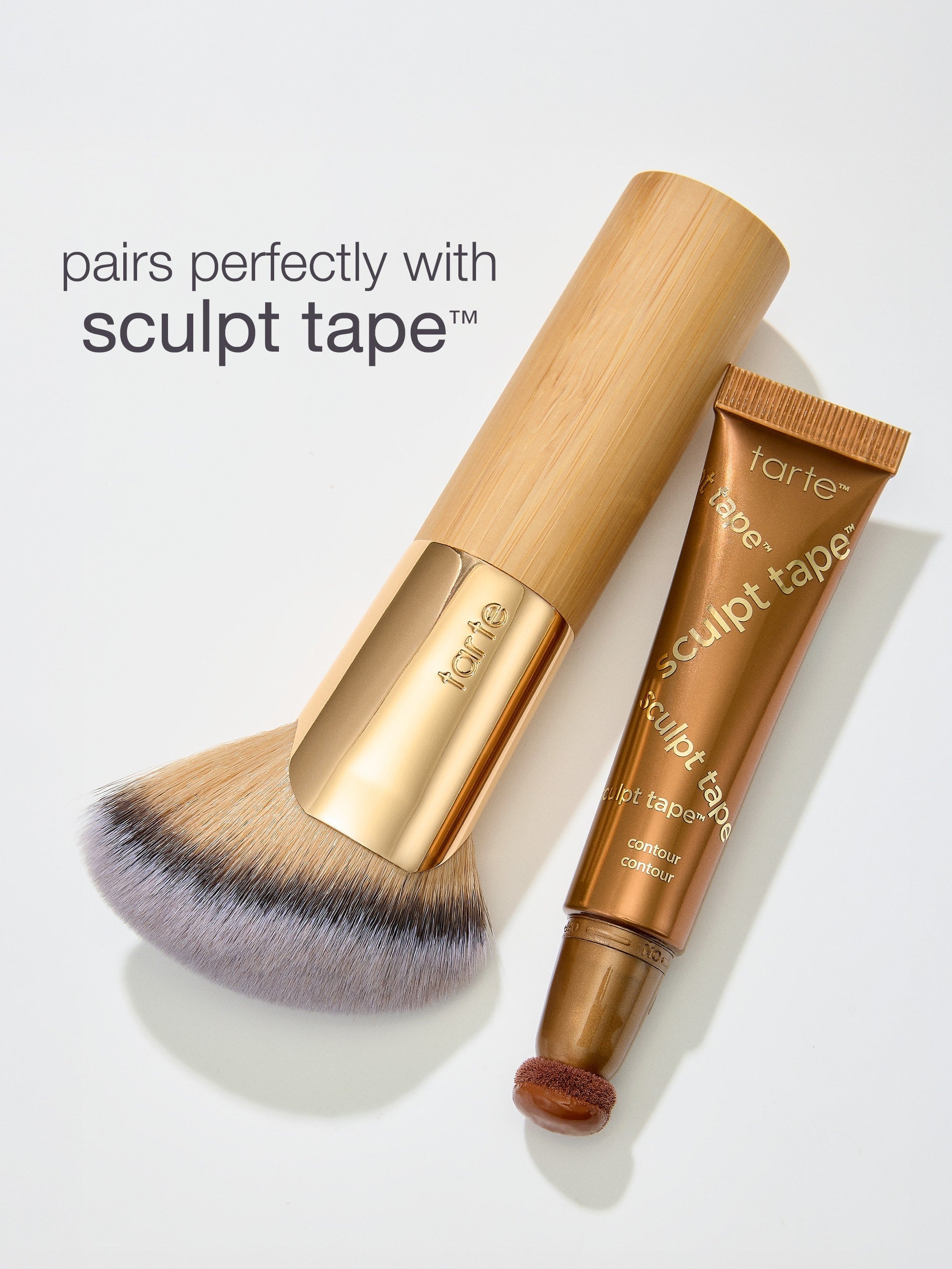 Makeup brush and 'sculpt tape' by tarte on a light gray background