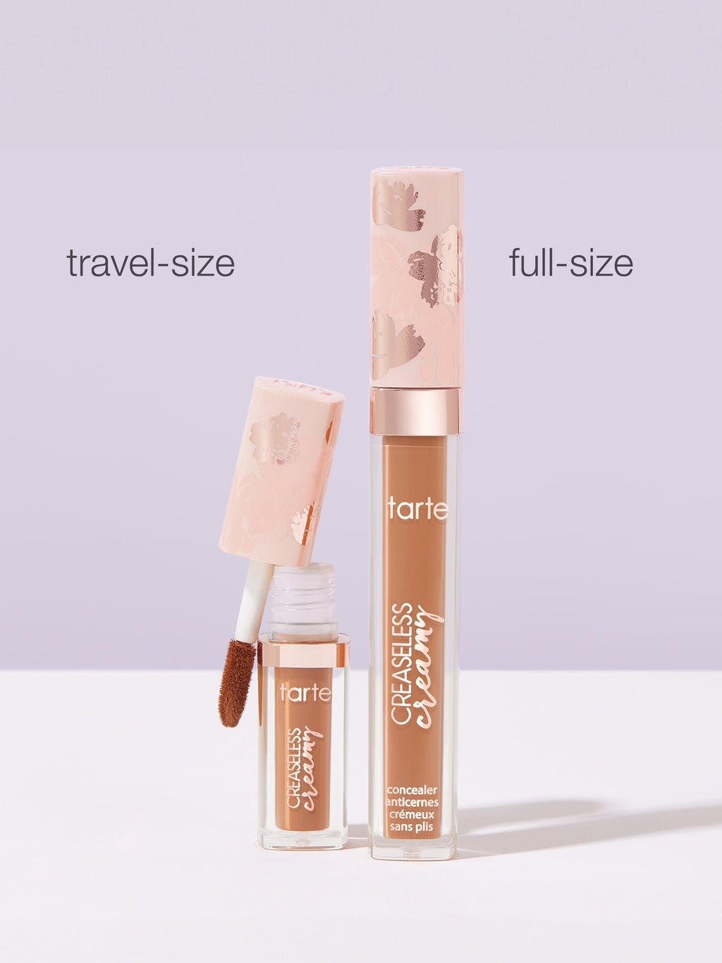 Two Tarte Cosmetics concealers stand against a light purple background. The left shows a travel-size with an open applicator; the right displays a full-size. Labels read travel-size, full-size, and CREASELESS creamy concealer anti-cernes crémeux sans plis.