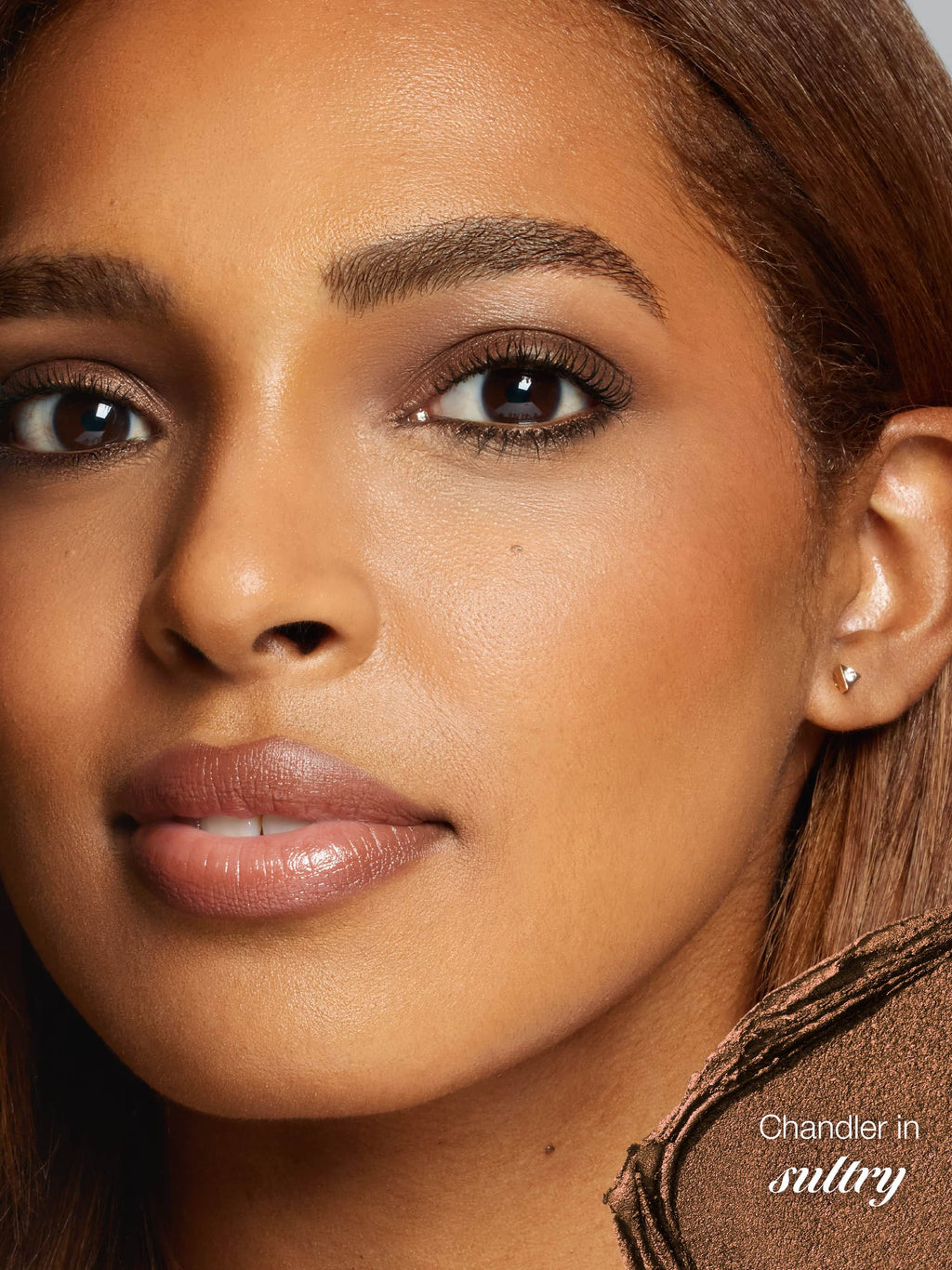 Close-up of a woman's face with a focus on her ear and hair, featuring the brand 'Chandler'.